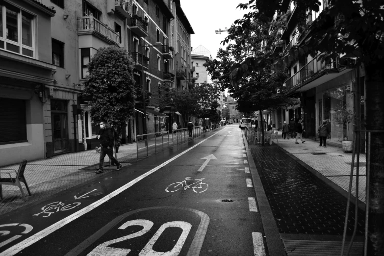 a black and white photo of a city street, by Modest Urgell, unsplash, cycling!!, taken on iphone 14 pro, day after raining, square