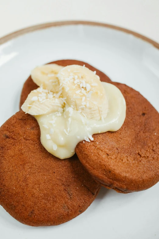 a couple of cookies sitting on top of a white plate, inspired by Richmond Barthé, banana, coconuts, kai'sa, pancakes