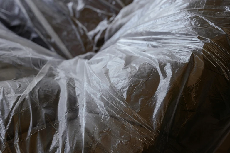 a donut covered in plastic sitting on top of a table, inspired by Sarah Lucas, unsplash, plasticien, feathered robe, folds, still from film, bags
