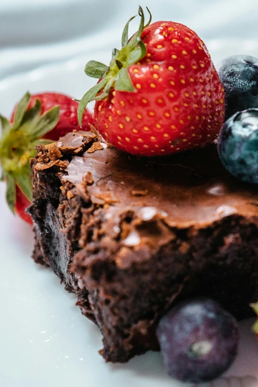 a piece of chocolate cake topped with strawberries and blueberries, pexels contest winner, renaissance, brown haired, edible crypto, flawless structure, profile image