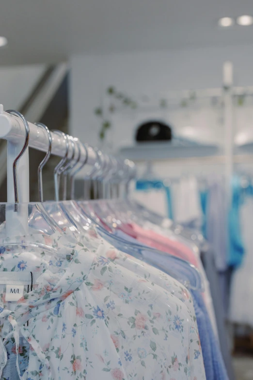 a rack of clothes in a clothing store, by Julian Allen, cinematic still, white and pale blue, flowery, sleepwear