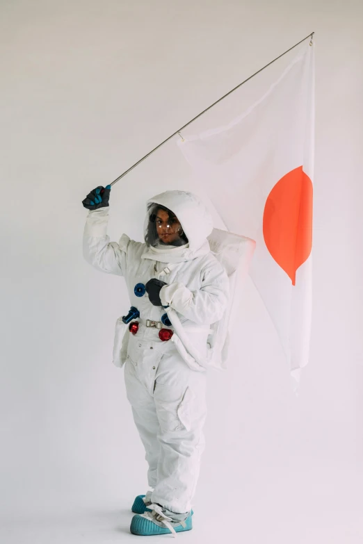 a man in a spacesuit holding a japanese flag, inspired by Koson Ohara, trending on unsplash, afrofuturism, white sky, studio photo, 2 0 0 0's photo, 2 0 1 0 s