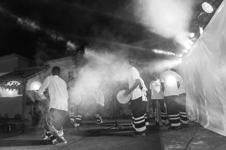 a group of men standing on top of a street, a black and white photo, pexels, figuration libre, summer festival night, real congas, in front of smoke behind, 2015