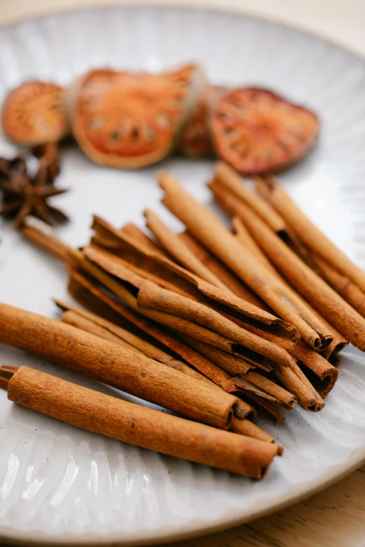 a white plate topped with cinnamon sticks and cloves, a portrait, inspired by Li Di, trending on pexels, botanicals, 王琛, vapor, bells