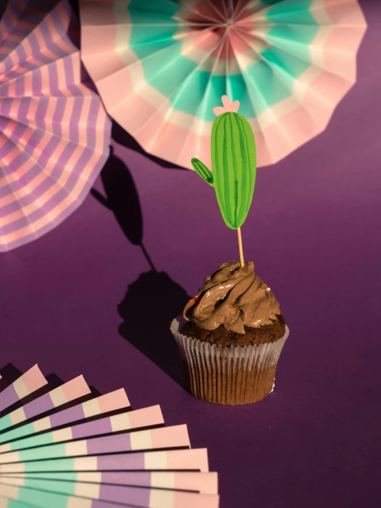 a cupcake sitting on top of a purple table, holding a cactus, product display photograph, diecut, dipstick tail