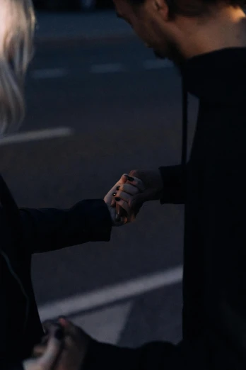 a man and a woman shaking hands in a parking lot, an album cover, inspired by Elsa Bleda, pexels contest winner, realism, in a black hoodie, woman in black robes, a blond, dark aesthetic