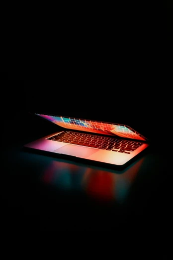 a laptop computer sitting on top of a table, by Byron Galvez, pexels, computer art, colourful dramatic lighting, on black background, gradient red, apple design