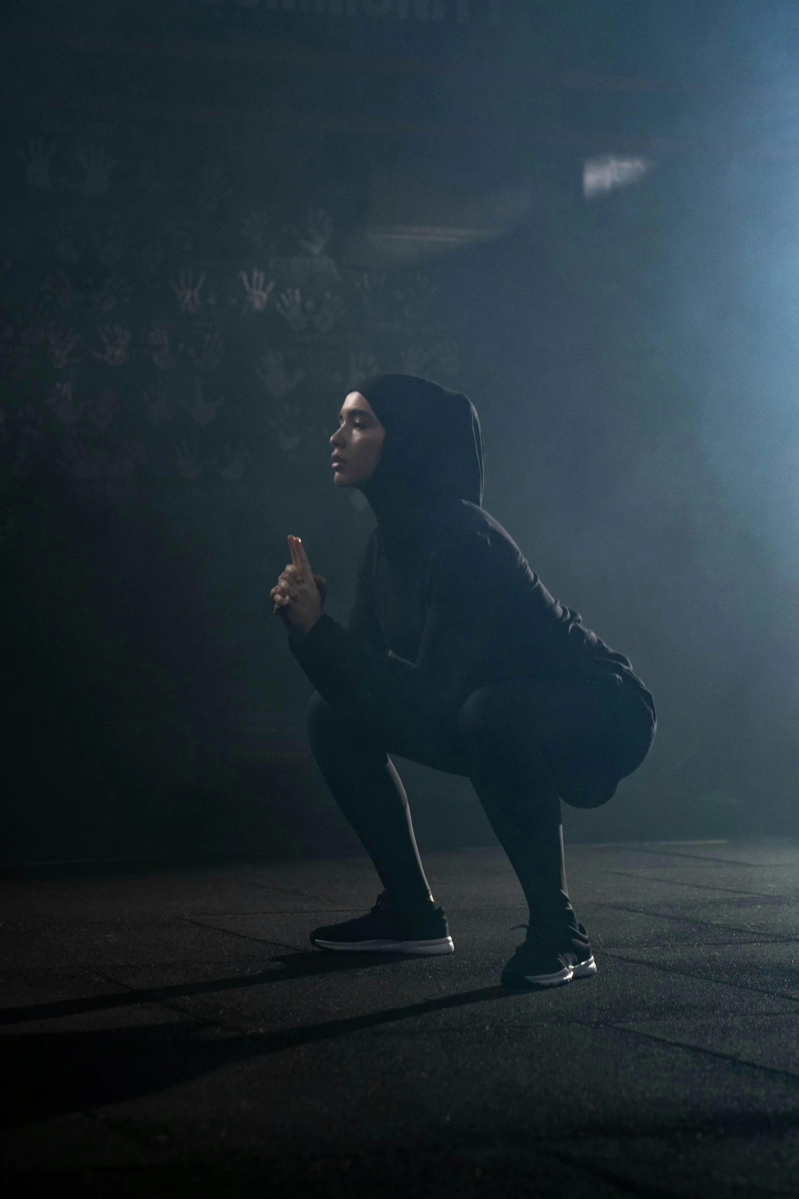a man kneeling on a skateboard in the dark, a hologram, inspired by Bernardino Mei, pexels contest winner, antipodeans, young middle eastern woman, in a gym, smoking with squat down pose, hijab