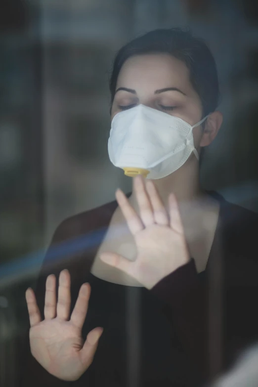 a woman wearing a face mask looking out a window, a picture, happening, hand over mouth, faint dust in the air, promo image, respirator