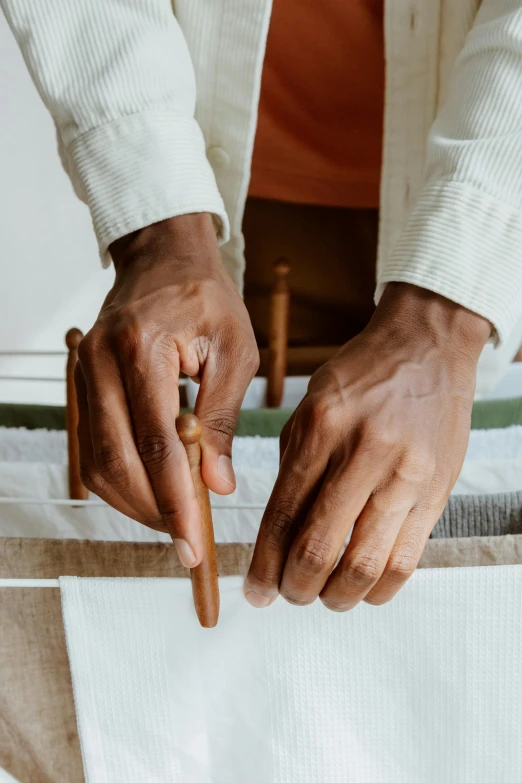 a person cutting a piece of paper with a knife, an album cover, inspired by Afewerk Tekle, trending on unsplash, arts and crafts movement, fabrics, wooden staff, wearing white cloths, thumbnail