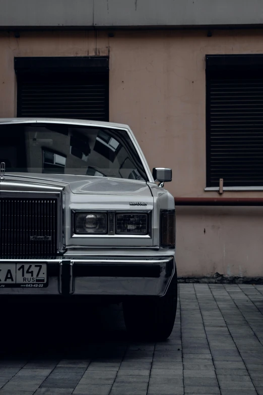 a silver car parked in front of a building, by Adam Marczyński, pexels contest winner, 1980's, mobster, white pearlescent, frontal picture