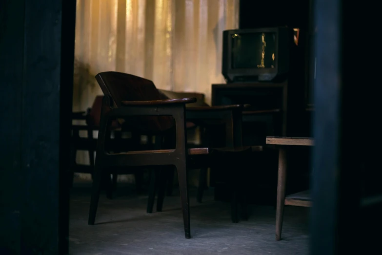 a chair sitting in front of a tv in a dark room, by Jesper Knudsen, modernism, cafe tables, old chairs, brown, post-war