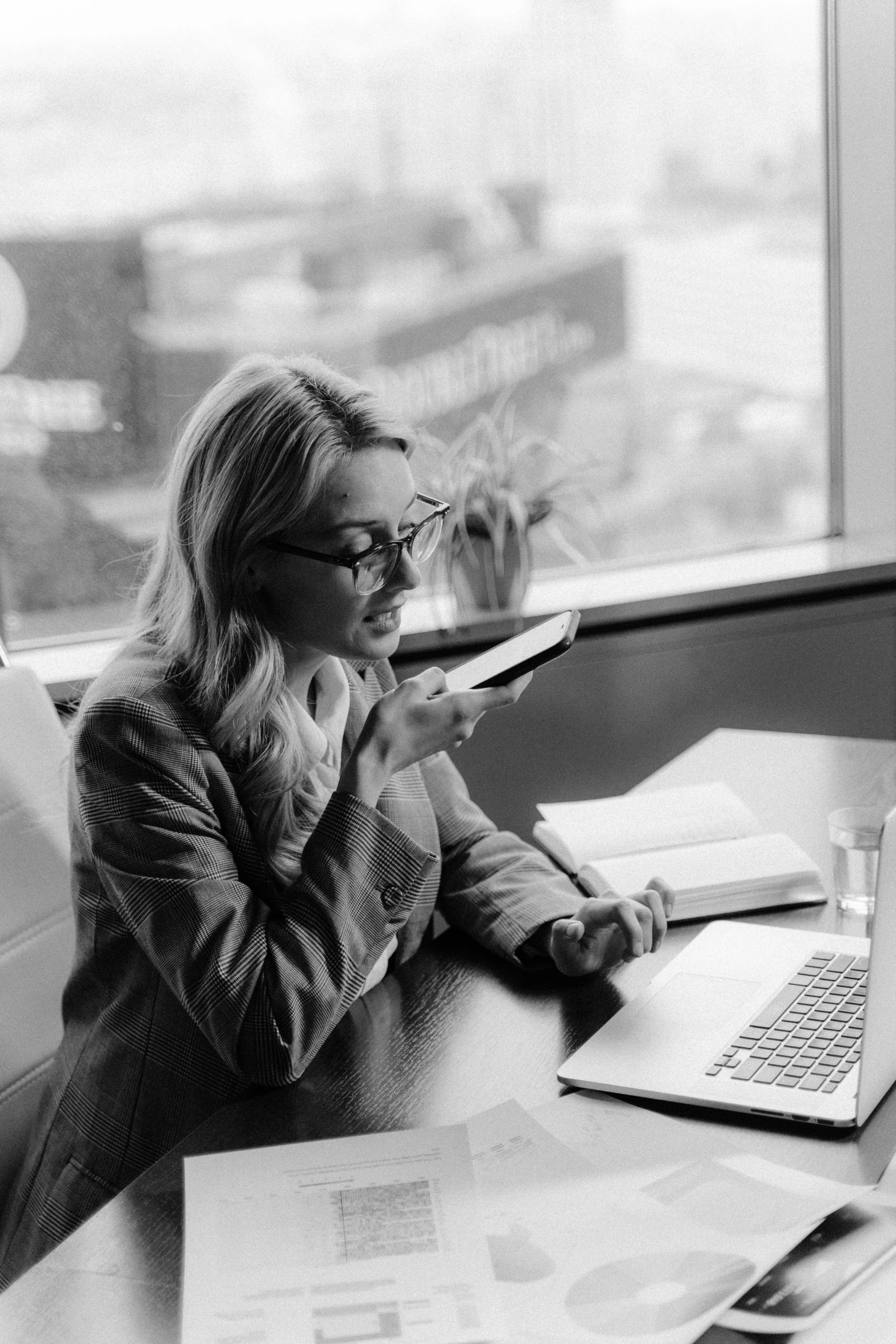 a woman sitting at a table with a laptop, a black and white photo, checking her cell phone, very professional, a blond, profile image