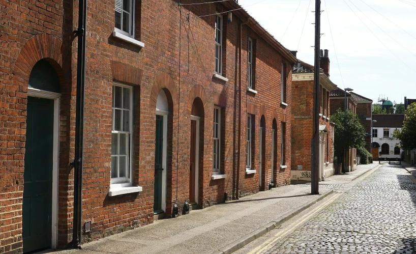 a cobblestone street lined with brick buildings, inspired by Stanley Spencer, unsplash, arts and crafts movement, tall terrace, eight eight eight, venetian red