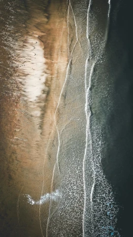 a man riding a surfboard on top of a sandy beach, by Neil Blevins, unsplash contest winner, minimalism, drone view, rivulets, abstract nature, water stream
