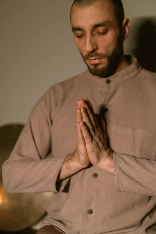 a man sitting on a couch with his hands folded in prayer, pexels, hurufiyya, wearing nanotech honeycomb robe, mid night, wearing a kurta, whirling