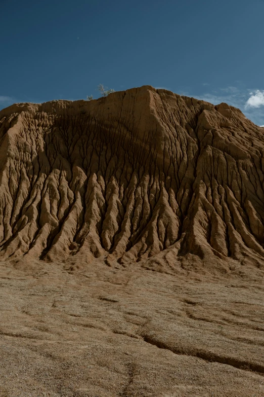 a man riding a surfboard on top of a sandy beach, a detailed matte painting, unsplash, land art, geological strata, folds, extreme panoramic, new mexico