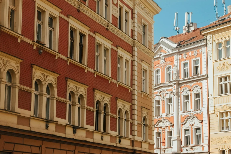 a group of people walking down a street next to tall buildings, inspired by Mihály Munkácsy, pexels contest winner, art nouveau, in legnica, red brown and white color scheme, square, old apartment