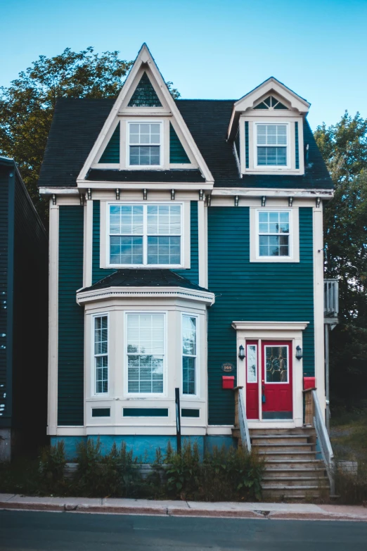 a blue and white house with a red door, by Sam Black, pexels contest winner, red green black teal, quebec, neighborhood themed, red brown and grey color scheme