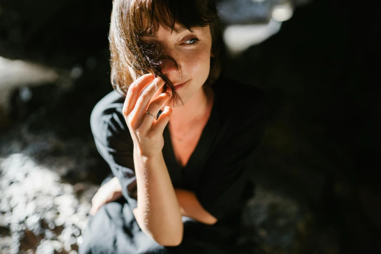 a woman in a black dress sitting on a rock, a portrait, by Julia Pishtar, pexels contest winner, portrait of max caulfield, medium format. soft light, in a cave, sydney hanson
