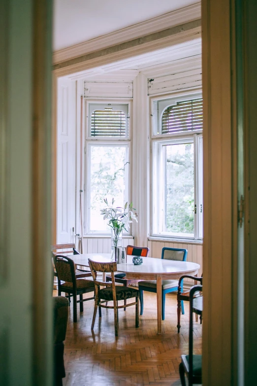 a dining room with a table and chairs, inspired by Constantin Hansen, unsplash, art nouveau, bay window, helsinki, retro style ”