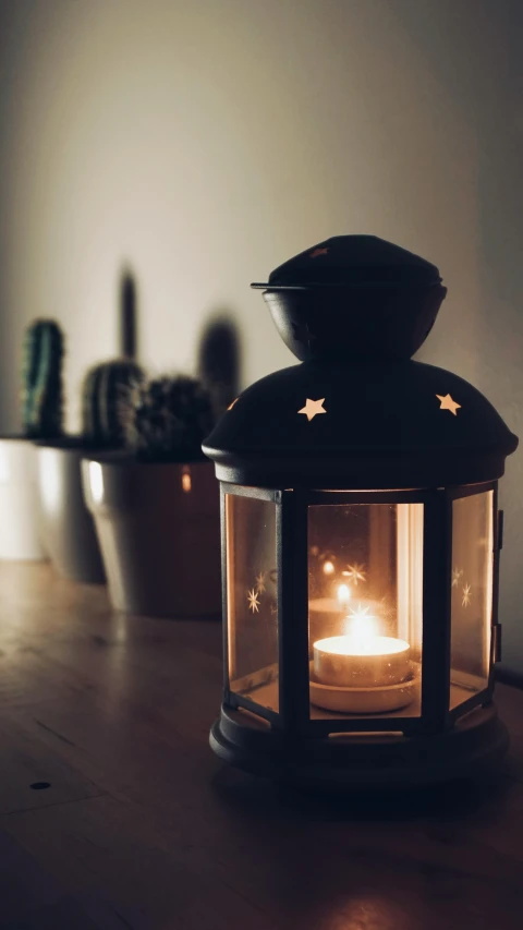 a lit candle sitting on top of a wooden table, pexels, light and space, lantern, instagram photo, cosy, starry