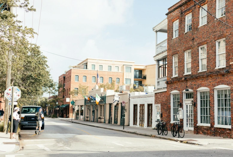 a man riding a bike down a street next to tall buildings, by Carey Morris, pexels contest winner, in savannah, storefronts, jen atkin, preserved historical