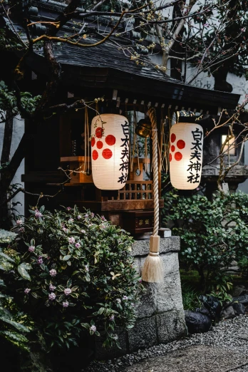 a couple of lanterns hanging from the side of a building, inspired by Kanō Shōsenin, trending on unsplash, ukiyo-e, lush surroundings, 2019 trending photo, beautifully soft lit, shrine