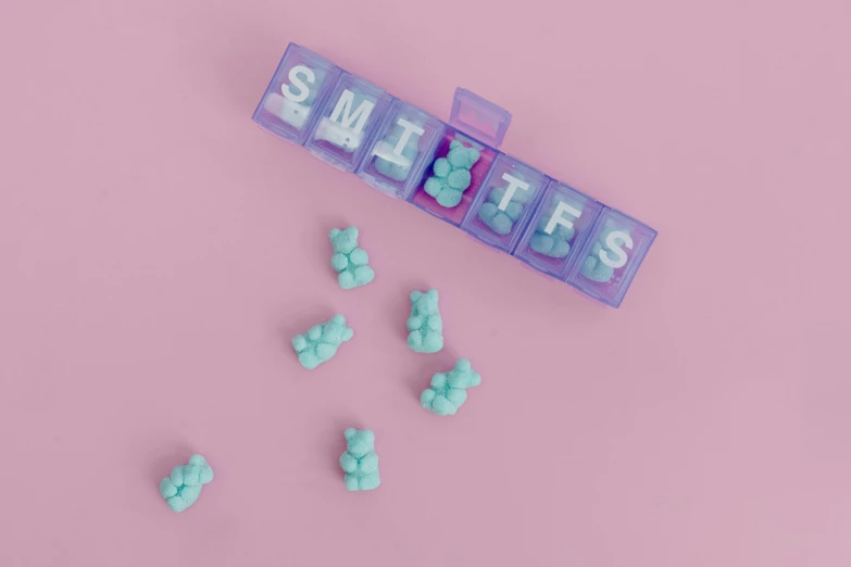 a pile of gummy bears sitting on top of a pink surface, an album cover, inspired by Cerith Wyn Evans, pexels contest winner, synthetism, pastel blue, letter s, switches, offering the viewer a pill