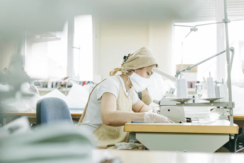 a woman working at a sewing machine in a factory, unsplash, avatar image, surgical gown and scrubs on, profile image, brown