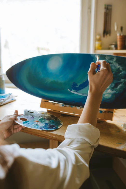 a woman is painting a surfboard on a table, by Adam Marczyński, full art, handcrafted, sup, recreation