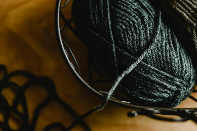 a ball of yarn sitting on top of a table, trending on pexels, arts and crafts movement, panel of black, anthracite, thumbnail, webbing