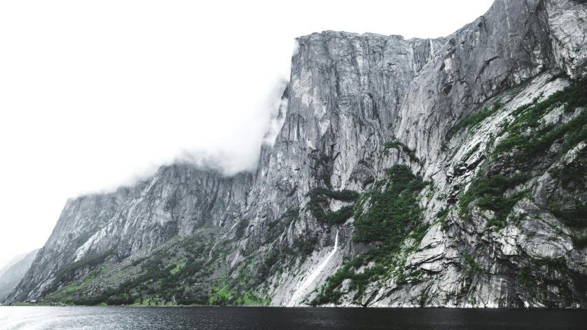 a body of water with a mountain in the background, by Roar Kjernstad, pexels contest winner, hyperrealism, steep cliffs, grey, full width, multiple stories