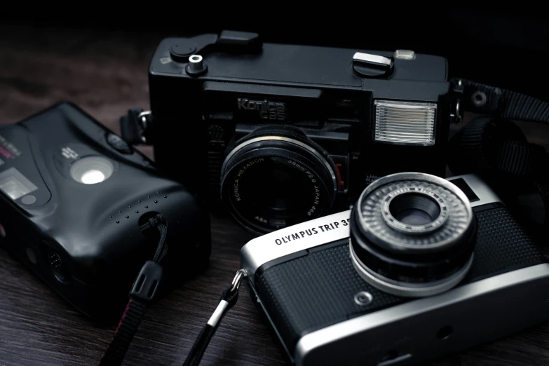 a couple of cameras sitting on top of a wooden table, a picture, by Adam Marczyński, medium format, old style photo, camera flash, miscellaneous objects