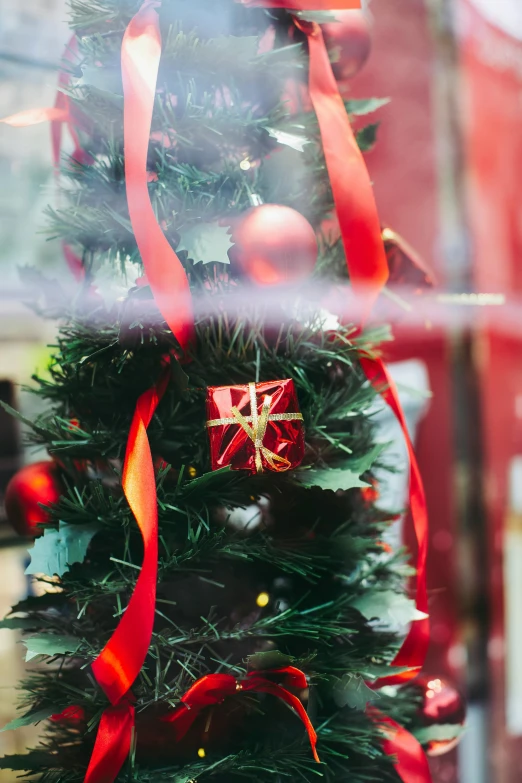 a close up of a christmas tree in a store window, red ribbon, ornament crown, small, swirling around