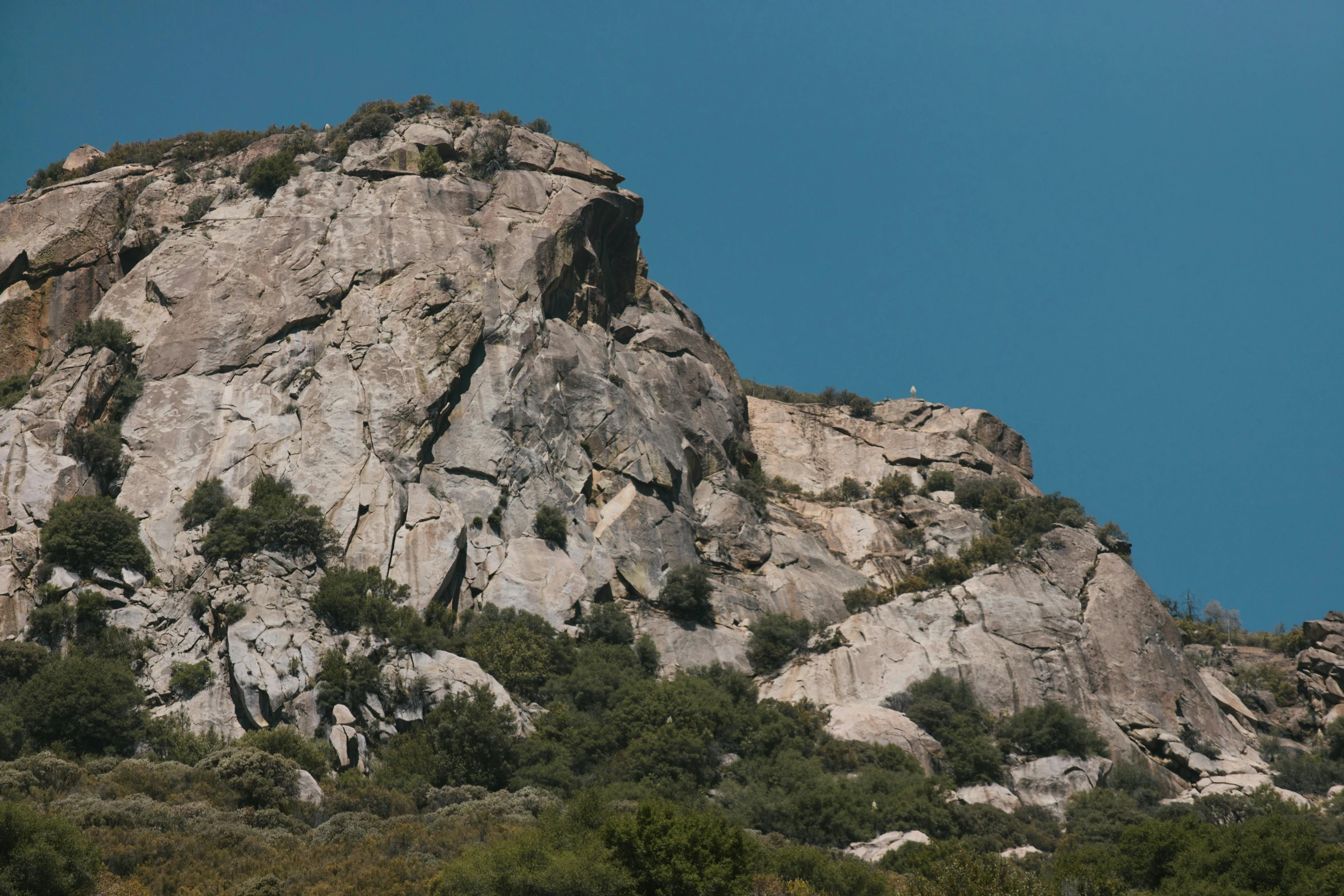 a group of people standing on top of a mountain, rock climbing, seen from a distance, clear blue skies, loomis