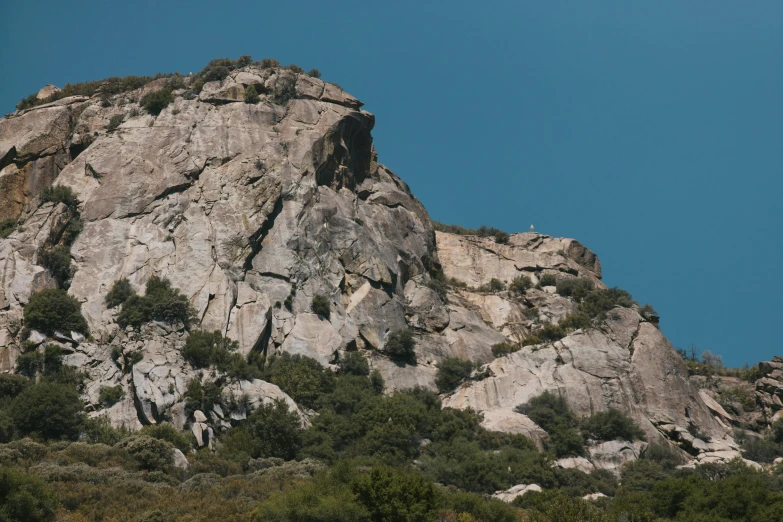 a group of people standing on top of a mountain, rock climbing, seen from a distance, clear blue skies, loomis