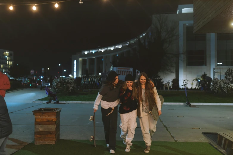 a group of people walking down a sidewalk at night, at a skate park, holding a cane, college girls, lawns