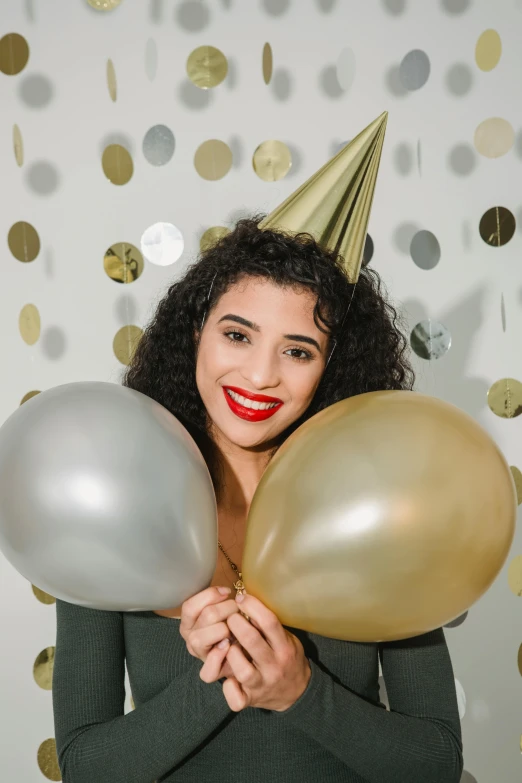 a woman in a party hat holding two balloons, trending on pexels, renaissance, young middle eastern woman, gold and silver shapes, curls, photo booth