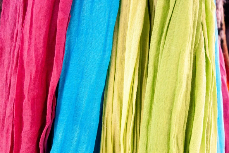 a bunch of different colored scarves hanging on a rack, flickr, color field, wearing a long flowy fabric, in the colors hot pink and cyan, medium closeup, some yellow green and blue
