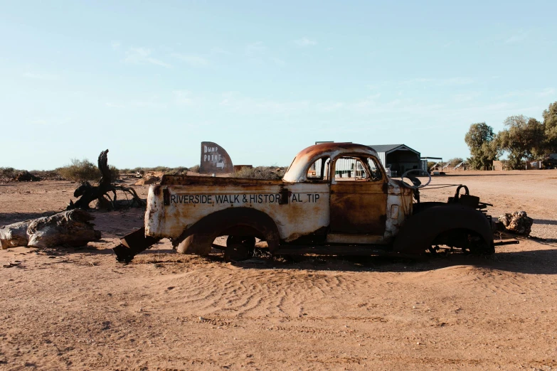 an old truck that is sitting in the dirt, by Jessie Algie, unsplash, auto-destructive art, old signs, outback, background image, old abandoned car sinking