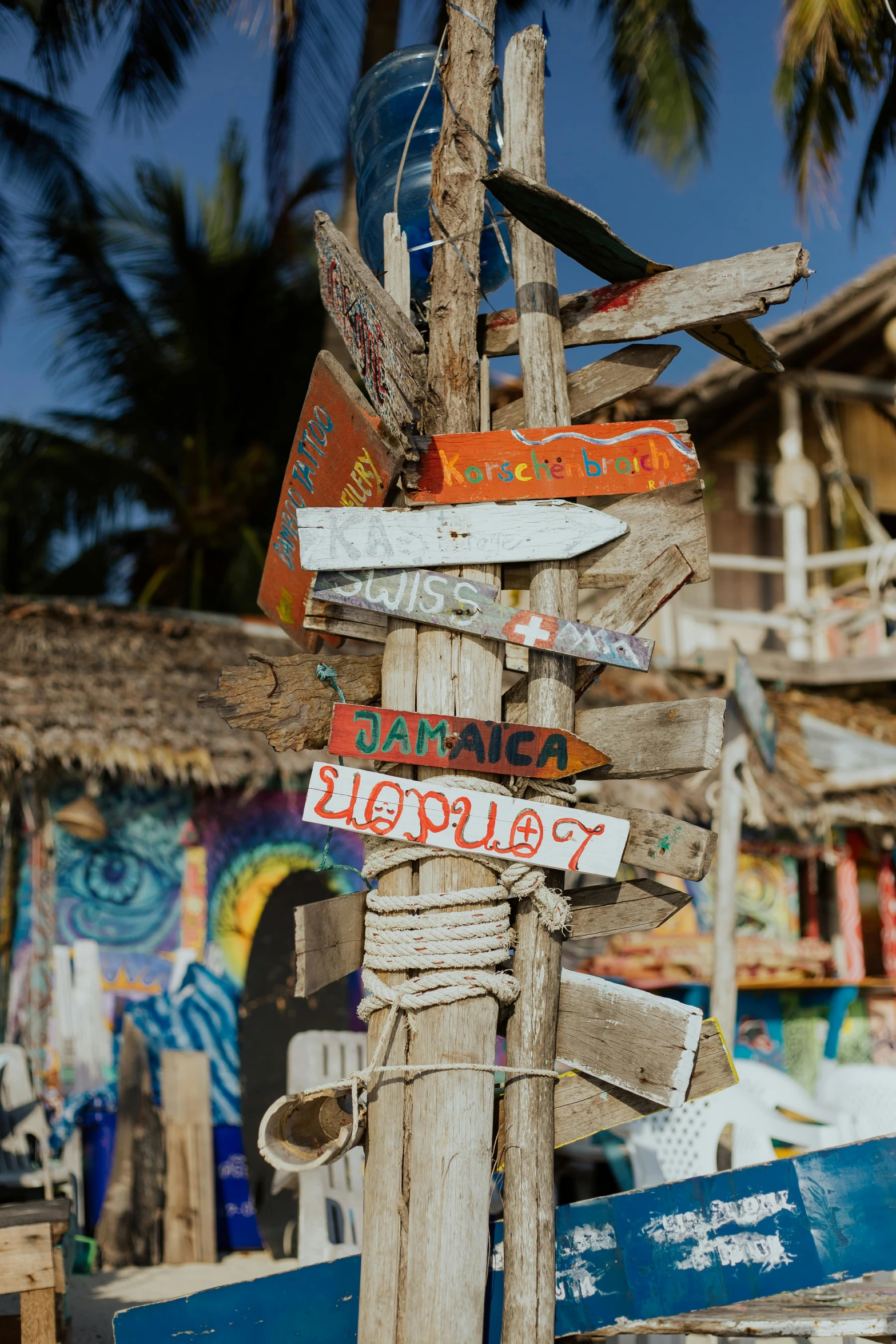 a wooden pole with a bunch of signs on it, by artist, trending on unsplash, graffiti, tropical location, beach bar, slide show, colorful houses