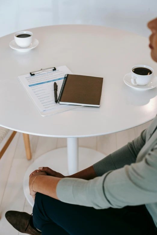 a man and a woman sitting at a table, pexels contest winner, private press, blank paper, a round minimalist behind, sitting on a mocha-colored table, ready for a meeting