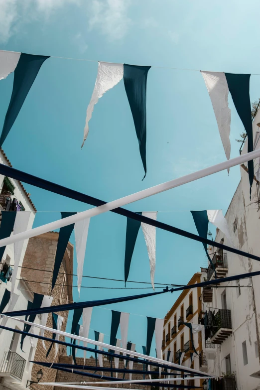 a street filled with lots of white and blue flags, trending on unsplash, costa blanca, rooftop party, seen from below, market setting