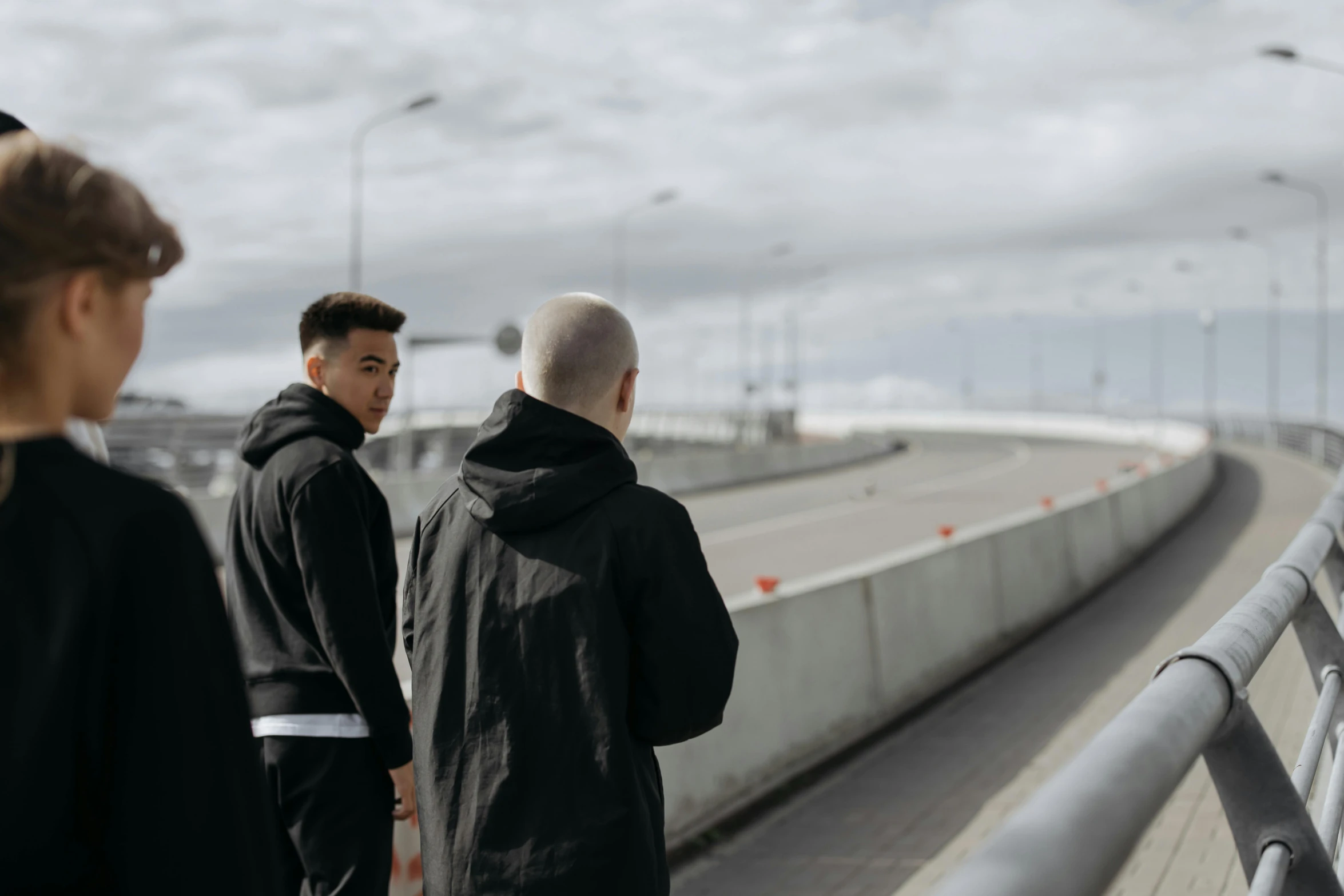 a group of men standing next to each other on a bridge, a picture, unsplash, antipodeans, wearing a track suit, nordic noire, two young men, roadside