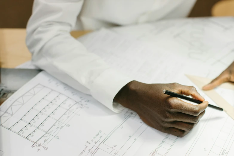 a person sitting at a table with a pen and paper, a drawing, engineering, subtle detailing, construction, commercial