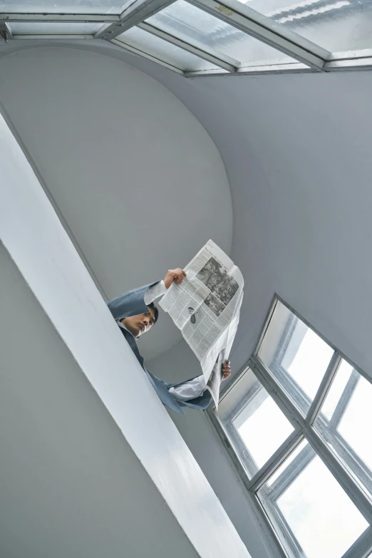 a man reading a newspaper on top of a staircase, a photocopy, by Ben Zoeller, trending on reddit, air conditioner, on grey background, architect studio, high angle vertical