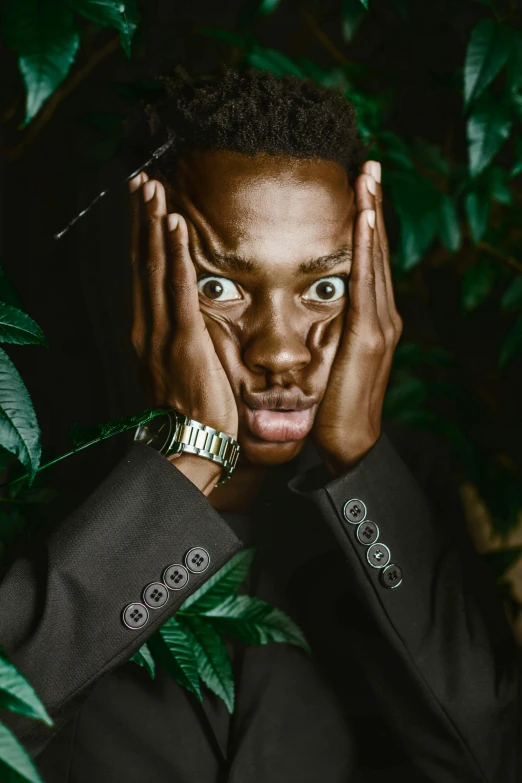 a man in a suit holding his hands to his face, an album cover, inspired by Barthélemy Menn, trending on pexels, lush greens, black teenage boy, wide eyed, instagram picture