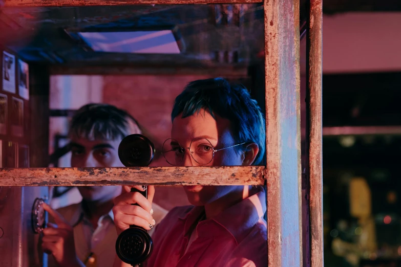 a woman taking a picture of herself through a window, by Lee Loughridge, pexels contest winner, still from a wes anderson film, red lighting on their faces, in foreground boy with shotgun, charli xcx