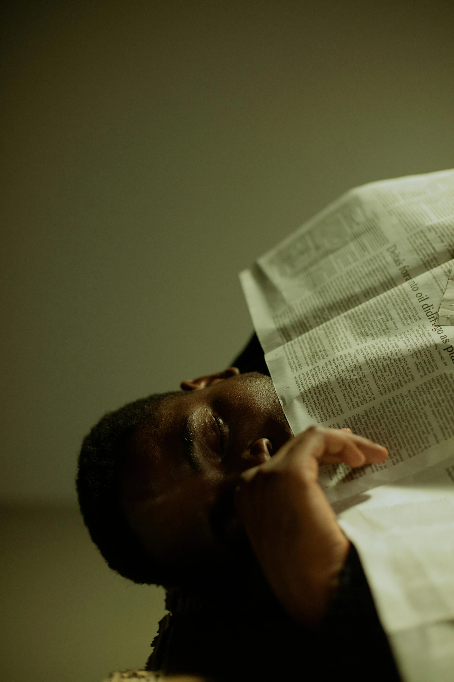 a person laying on a bed reading a newspaper, a photocopy, by Adam Chmielowski, dark-skinned, face shot, upsidedown, shoulder